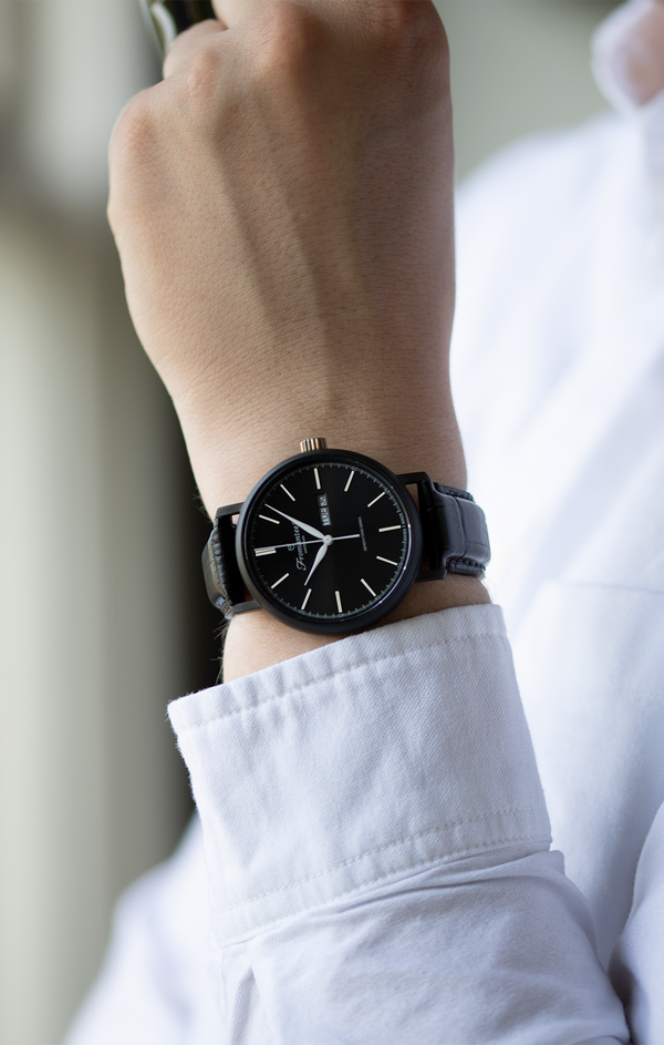 Male wrist adorned with the all-black PVD coated Fromanteel Day Date Nero watch, showcasing sleek elegance and modern design.